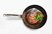 A fried beef steak in a pan (seen from above)