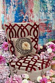 An upholstered chair with a burn-out pattern and a cushion in a sea of hydrangeas, roses and dahlias