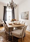 Beige gepolsterte Stühle an rustikalem Esstisch mit Kronleuchter in Wohnzimmerecke mit traditionellem Flair