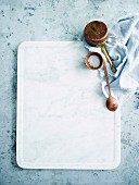 White chopping board with salt, spoon and copper pot