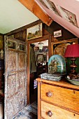 Antique objects on top of chest of drawers next to open wooden door