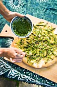 Vegan potato and asparagus pizza being drizzled with wild garlic sauce