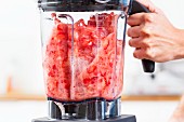Strawberries being puréed in a blender