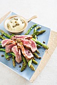 Slices of beef steak on green asparagus with a Béarnaise caper sauce