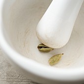 Cardamom capsules being crushed in a mortar