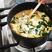 Potato cauliflower curry with spinach being stirred