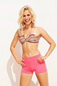 Blonde Frau in pinken Shorts und bunt gestreiftem Bikinioberteil