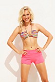 Blonde Frau in pinken Shorts und bunt gestreiftem Bikinioberteil