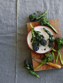 Fresh broccoli on a chopping board and on a plate (seen from above)