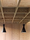 Retro pendant lamps with black metal lampshades suspended from modern coffered ceiling in pale wood