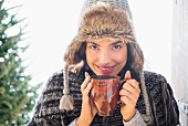 A woman wearing a fur hat holding a cup of coffee