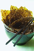 Seaweed leaves in a bowl with chopsticks