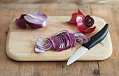 Red onions, sliced with a knife on a chopping board