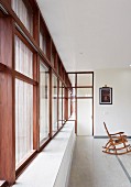 Purist interior of modern, Indian house with stone floor and continuous strip of wood-framed windows