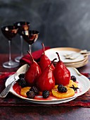 Poached red wine pairs with blackberries and orange slices