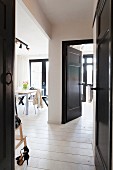 Blick durch offene, schwarz lackierte Tür auf Essplatz, in Wohnraum mit schwarz weissen Farbakzenten