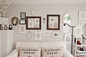 White sofa with hessian scatter cushions below pictures and picture frames on wall