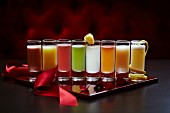 A row of shot glasses filled with different coloured cocktail
