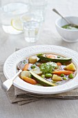 Courgette soup with carrots, potatoes, peas and pesto