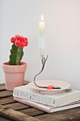 Lit candle on candlestick made from bent vintage fork stuck to saucer with washi tape in ront of flowering cactus