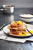 A stack of pancakes with oranges and cranberries