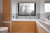 Badezimmer mit massgefertigten Einbauten aus Holz, Badewanne am Fenster
