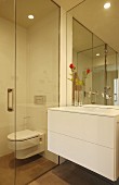 White washstand with drawers next to glazed toilet cubicle