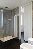 Modern bathroom with white sanitary suite, glass shower cabinet and tiled walls