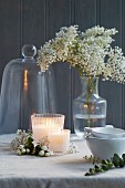 Festlich gedeckter Tisch mit Kerzen, Blumenvase, Cloche und Schälchen