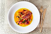 Fried fillet of fish with courgette curls, tomatoes and orange