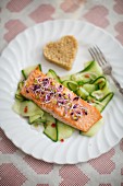 Salmon fillet with bean sprouts on a cucumber salad with a heart-shaped piece of bread