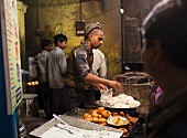 Traditionelles Street Food (Reisfladen und Aloo Tikki Bratkartoffeln) bei einem Straßenstand in Varanasi, Indien