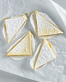 Lemon tart triangles with icing sugar on white parchment paper
