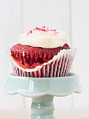 A Red Velvet cupcakes with white frosting on a cake stand (close-up)