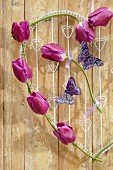 Drahtherz dekoriert mit lilafarbenen Tulpen der Sorte Purple Flag & Schmetterlingen als Wandschmuck