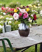 Rosenstrauss aus verschiedenfarbigen Rosen auf Gartentisch