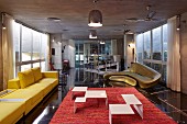 Delicate coffee table in white-painted metal on red rug, yellow sofa and golden sofa by Zaha Hadid