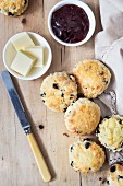 Scones with jam and butter on a wooden table with a cloth