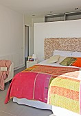 Patchwork bedspread on double bed against partition in bedroom