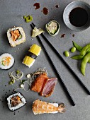 Nigiri sushi, California rolls, maki sushi and sashimi on a grey surface