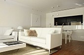 White designer furniture in open-plan interior with dining area next to kitchen pass-through