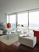 Designer-Wohnraum mit Möbeln aus Acrylglas und Farbakzenten in Orange und Meerblick