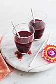 Two beetroot smoothies in glasses with straws