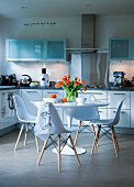 Modern kitchen with white cupboards and Tulip table and chairs in centre