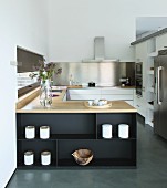 Elegant fitted kitchen with U-shaped counter decorated with pots and olive-wood bowl in purist style