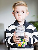A boy holding a jar of bonbons