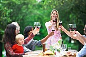 Friends raising glasses of red wine at a garden party