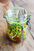 Vegetable salad with sweetcorn, beans and radishes in preserving jar
