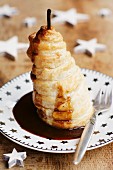 A baked pear wrapped in pastry with a spicy caramel sauce