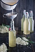 Homemade elderflower syrup being poured into bottles